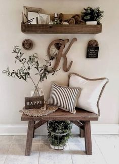 a wooden bench topped with pillows next to two shelves filled with plants and other items