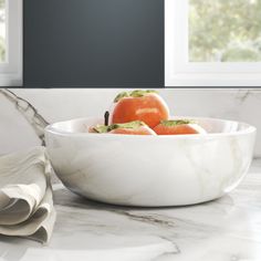 a marble bowl filled with tomatoes on top of a counter