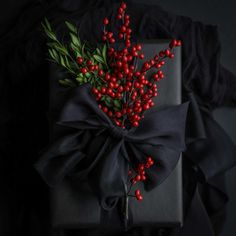 a present wrapped in black paper with red berries on it