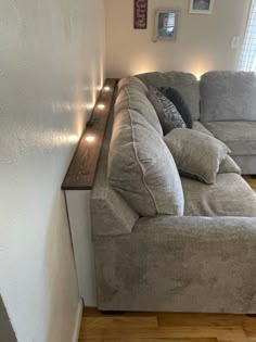 a living room with a couch and some lights on the side of the wall in front of it