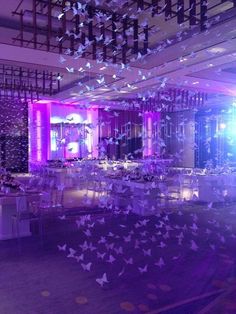 a large room filled with lots of tables covered in purple and white butterfly decorations on the ceiling