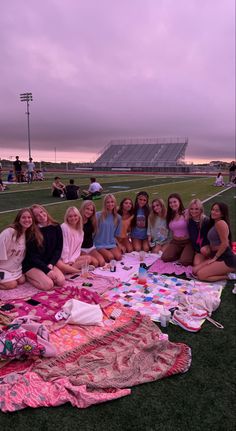 a group of women sitting on top of a field next to each other