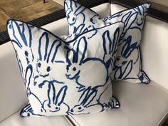 two blue and white pillows sitting on top of a couch