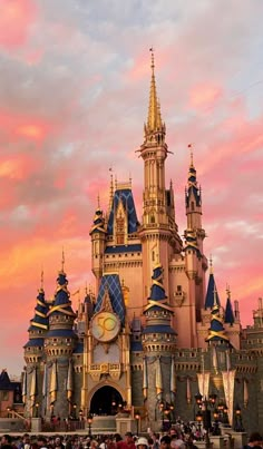 people are standing in front of a castle at sunset with the sun setting behind it