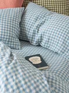 a book is laying on top of a bed with blue and white checkered sheets