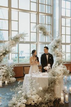 a man and woman standing next to each other in front of a table with candles