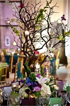 the centerpiece is decorated with branches, flowers and candles for an elegant touch to the table