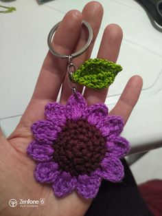 a crocheted flower keychain is being held in someone's hand