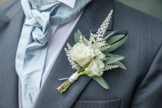 a boutonniere with white flowers and greenery is worn on a man's suit