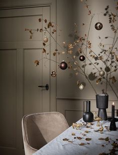 a dining room table with ornaments hanging from the ceiling and candles in vases next to it