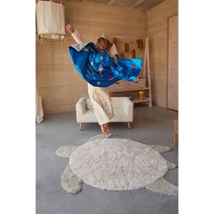 a woman in a blue kimono is doing a handstand on a turtle rug