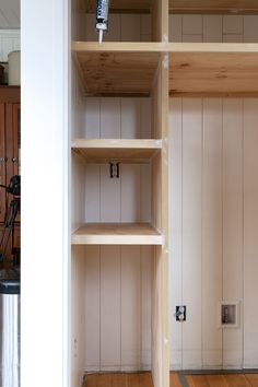 an empty shelf in the corner of a room with wood flooring and white walls