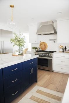 a kitchen with blue cabinets and white countertops is pictured in this image, there is a rug on the floor next to the stove