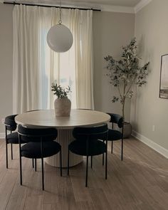 a dining room table with four chairs and a potted plant in the center on top