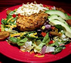 a red plate topped with salad and meat