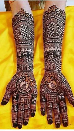 two hands with henna designs on them, one is showing off the intricate design