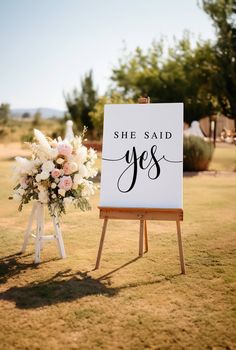 a sign that says she said yes with flowers on it in front of an easel