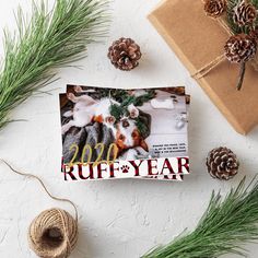 a christmas card with a dog on it next to some pine cones and twine