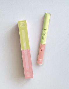 a pink and green toothbrush sitting on top of a white table next to a box