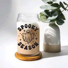 a glass jar with spooky season written on it next to a potted plant