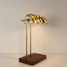 a table lamp with a stained glass shade on it's base and wooden stand