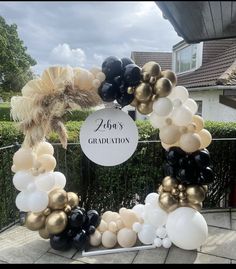 a graduation balloon arch with black, white and gold balloons