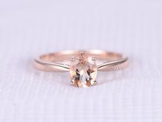 an oval shaped morganite sits on top of a thin band in this engagement ring