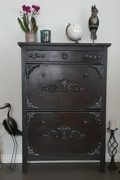 a black dresser with ornate carvings and flowers on top