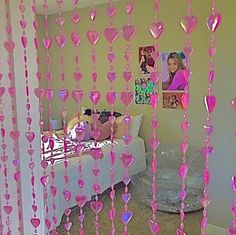 a bedroom with pink hearts hanging from the ceiling and pictures on the wall behind it