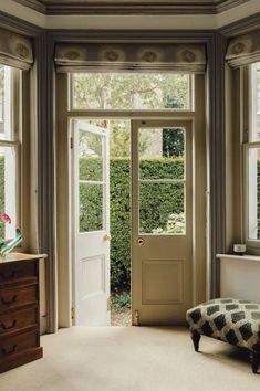 a room with two windows and a bench in front of the door that leads to another room