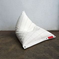 a white pillow sitting on top of a wooden floor next to a wall and cement floor