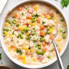 a bowl of chicken and vegetable soup with a spoon in the bowl next to it