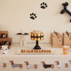 a table topped with cakes and cupcakes next to a wall mounted dog paw prints