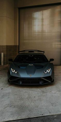 a blue sports car parked in front of a garage door with roller shades on it