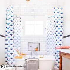 the bathroom is decorated in white and blue colors with an interesting pattern on the shower curtain