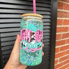 a hand holding a pink and blue glittered cup with the words mama on it