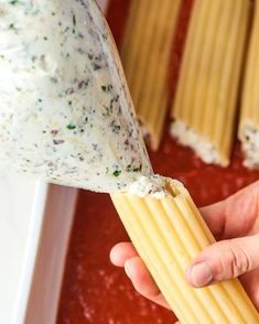 someone is dipping some kind of sauce on top of pastasticks in a pan