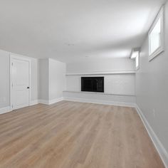 an empty room with hard wood flooring and white painted walls, along with a fireplace