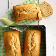 two loafs of bread sitting on top of a green and white checkered cloth