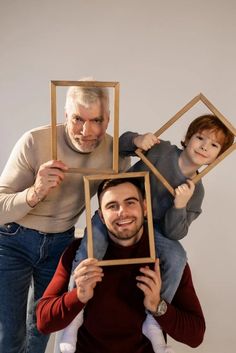 an older man and two young boys holding up pictures in front of their faces to show them