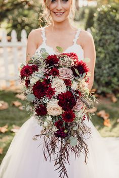 a bride holding a bouquet of red and white flowers