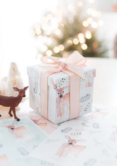 a small deer figurine next to a gift box with a pink bow on it