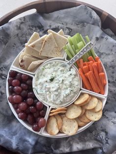 a platter with crackers, grapes, carrots, celery and crackers