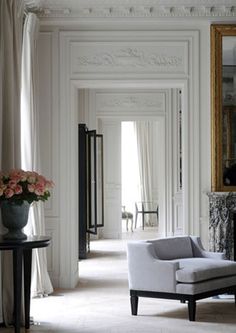 a room with white walls and flooring has flowers in a vase on the table