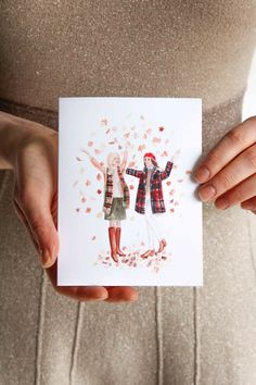 a woman holding up a card with two women in plaid outfits on it's hands