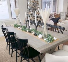 a dining room table with candles, flowers and greenery on the long centerpiece