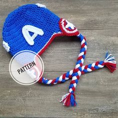 a crocheted hat with the letter a on it sitting on a wooden surface