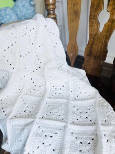 a white crocheted blanket sitting on top of a wooden chair