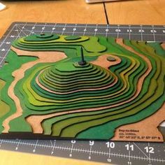 a cutting board with an image of a green landscape on it and a ruler next to it