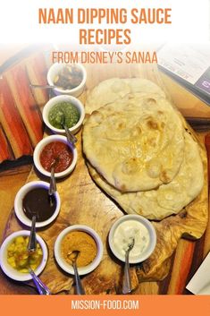 a wooden table topped with lots of different bowls and sauces next to an uncooked pita bread